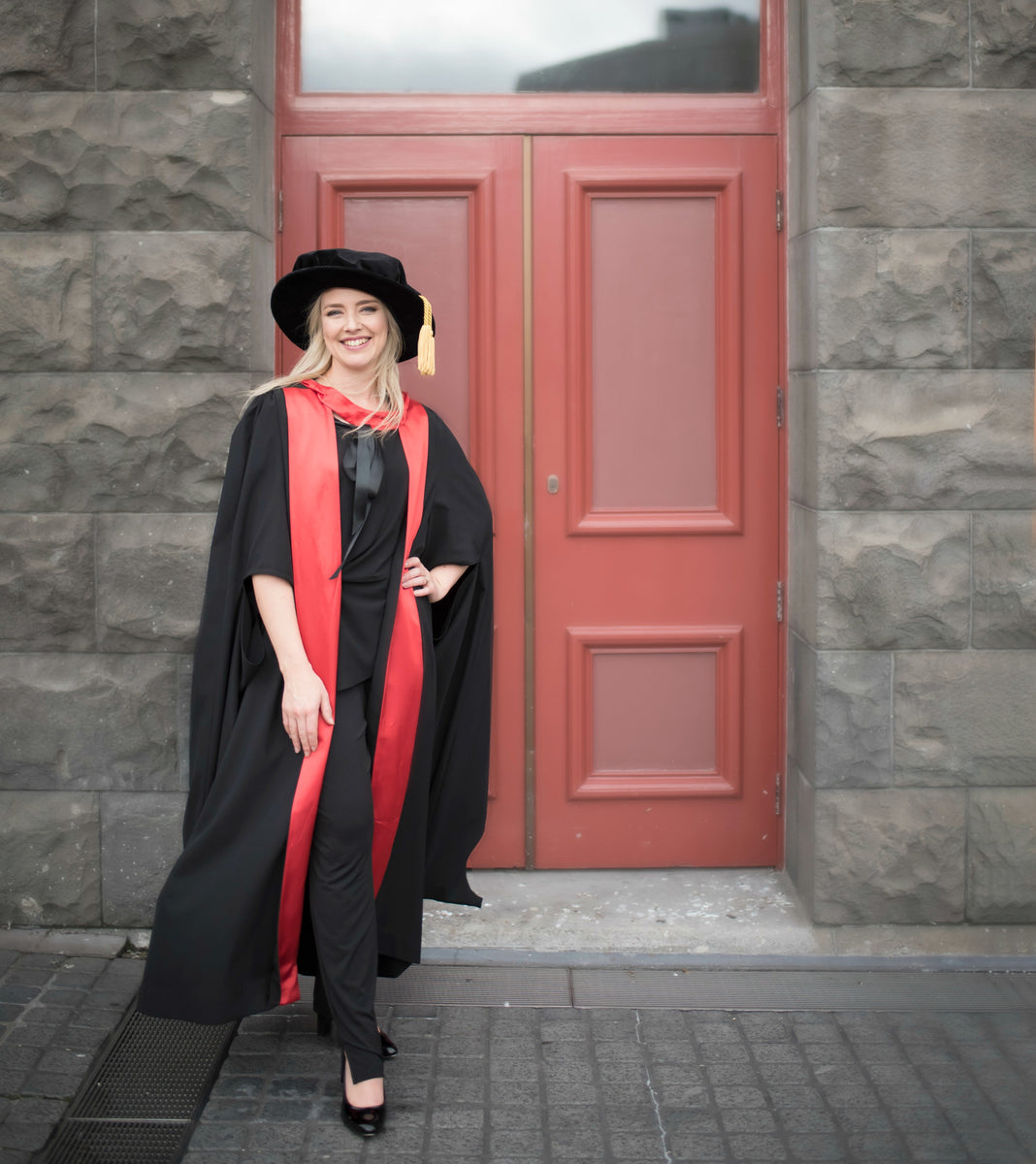 Graduation outfit of Dr Julie Bhosale, standing outside of door and smiling
